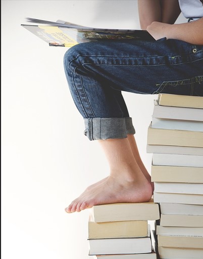 책을 많이 쌓아놓고 앉아서 읽고 있는 사진