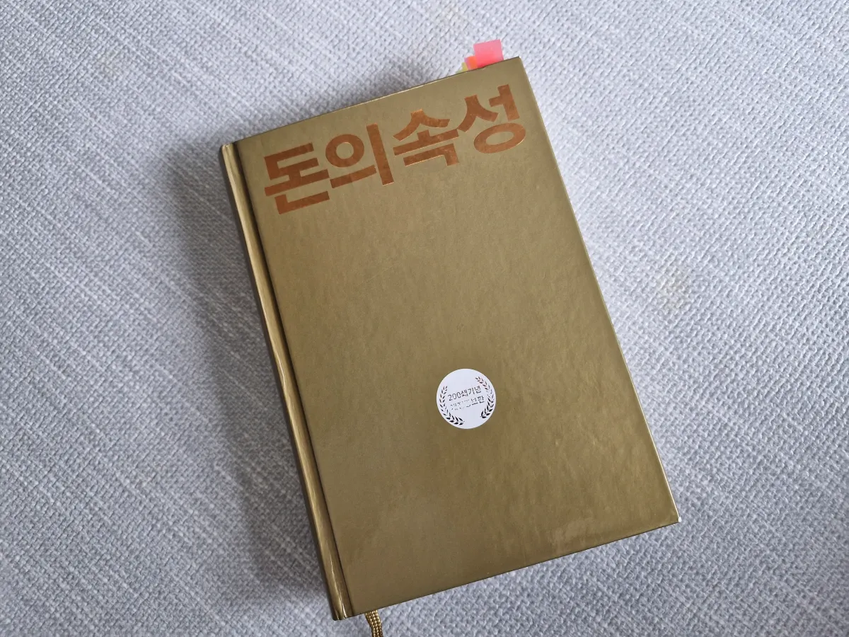 바닥위에-올려져-있는-황금색의-돈의-속성-책