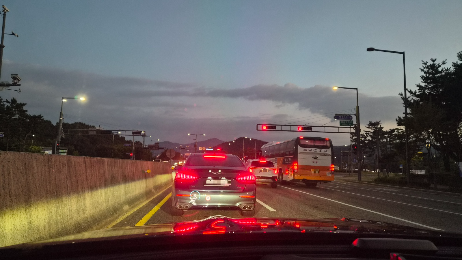 도로 위 신호대기 중 차량 정차 모습, 앞차와 버스가 정지해 있는 시내 주행 상황