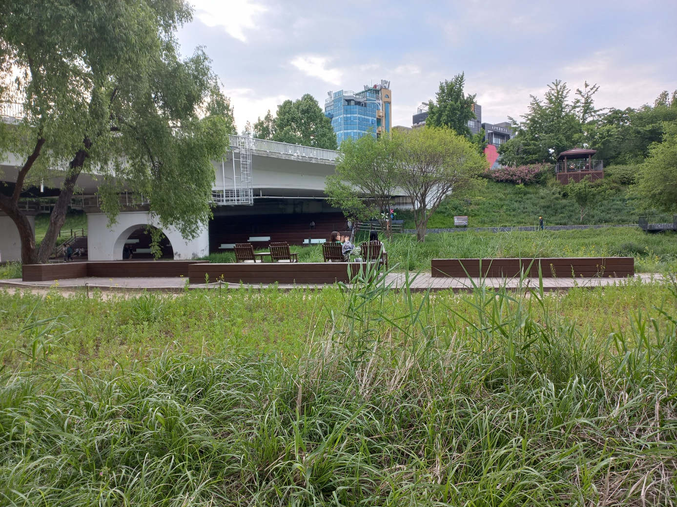 두 여자가 벤치에 앉아 양재천을 바라보고 있음