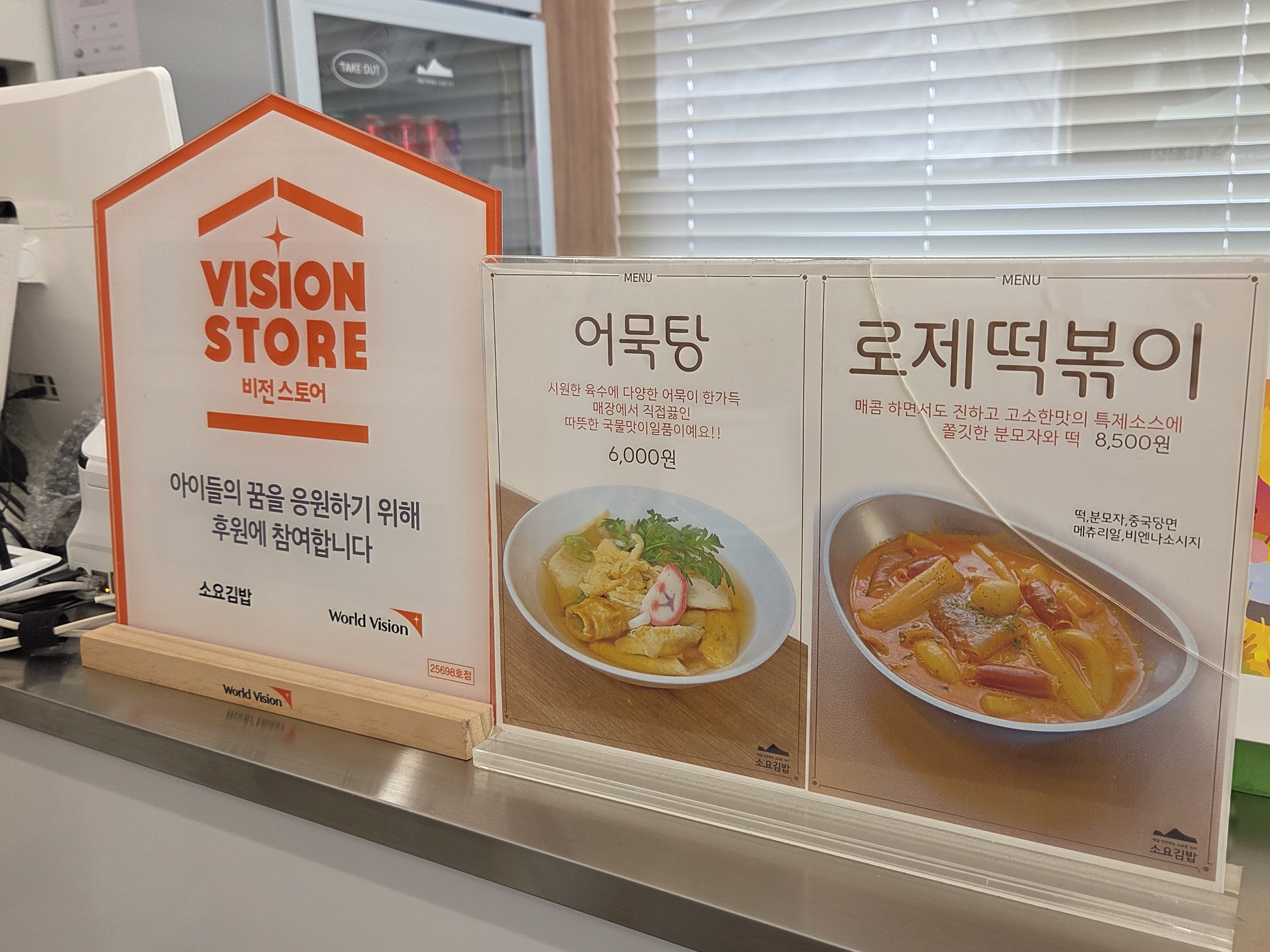 매장 카운터 위 비전 스토어 안내와 어묵탕, 로제 떡볶이 메뉴 안내판.