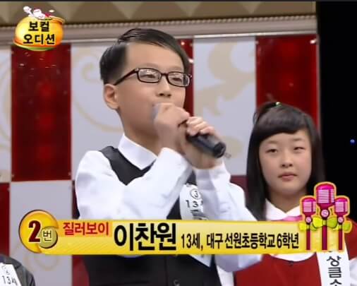 13세 이찬원 공중파 보컬오디션에서 마이크 잡고 노래 부르는 모습, 안경을 쓰고 있습니다.