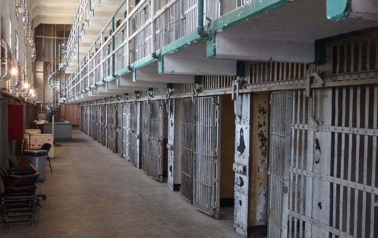 철제 문과 복도가 늘어선 교도소 내부 전경. 영화 7번방의 선물의 수감 장면과 유사한 분위기.