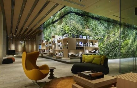 의자와 테이블이 놓여져 있고 뒤로 식물로 되어 있는 담이 보인다.