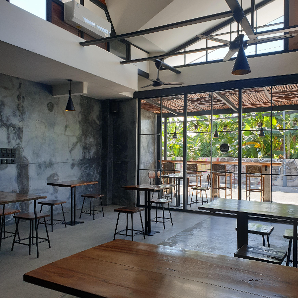 천정에는 팬이고 벽면에는 에어컨이 보인다. 전면은 커다란 유리로 된 문과 창이 있다. 바닥과 벽면은 노출 콘크리트. 인더스트리얼 감성