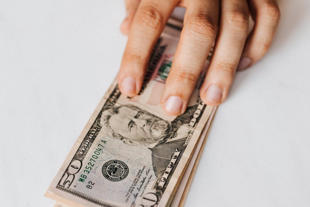손으로 쥔 50달러 지폐로 표현한 보험금 수령