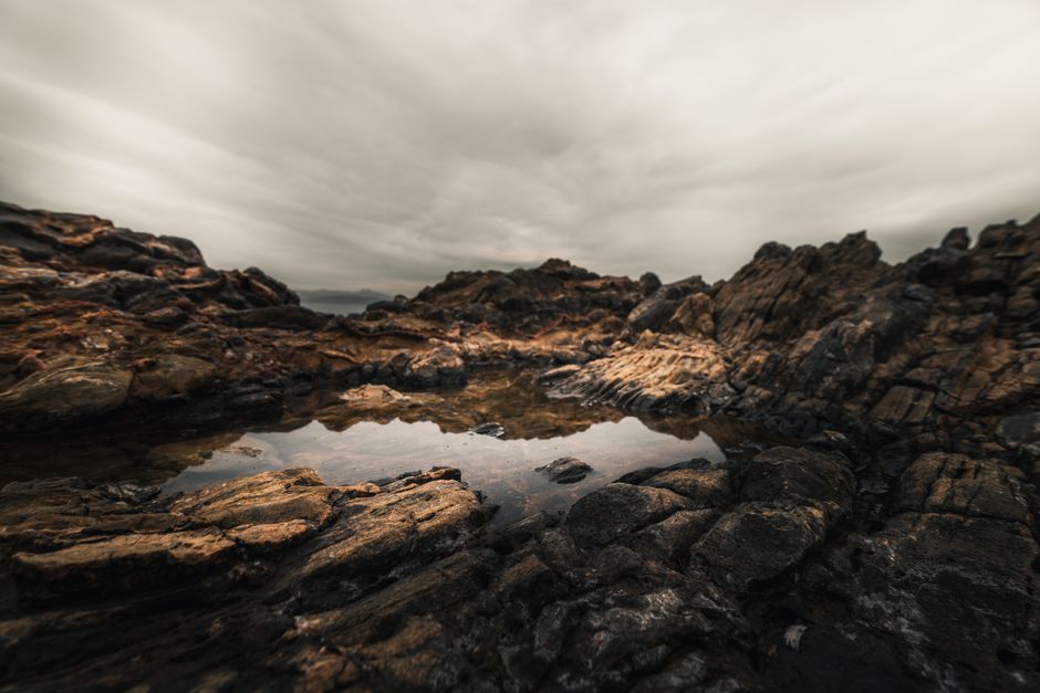 A captivating rocky shoreline with dramatic clouds reflected in tidal pools.
