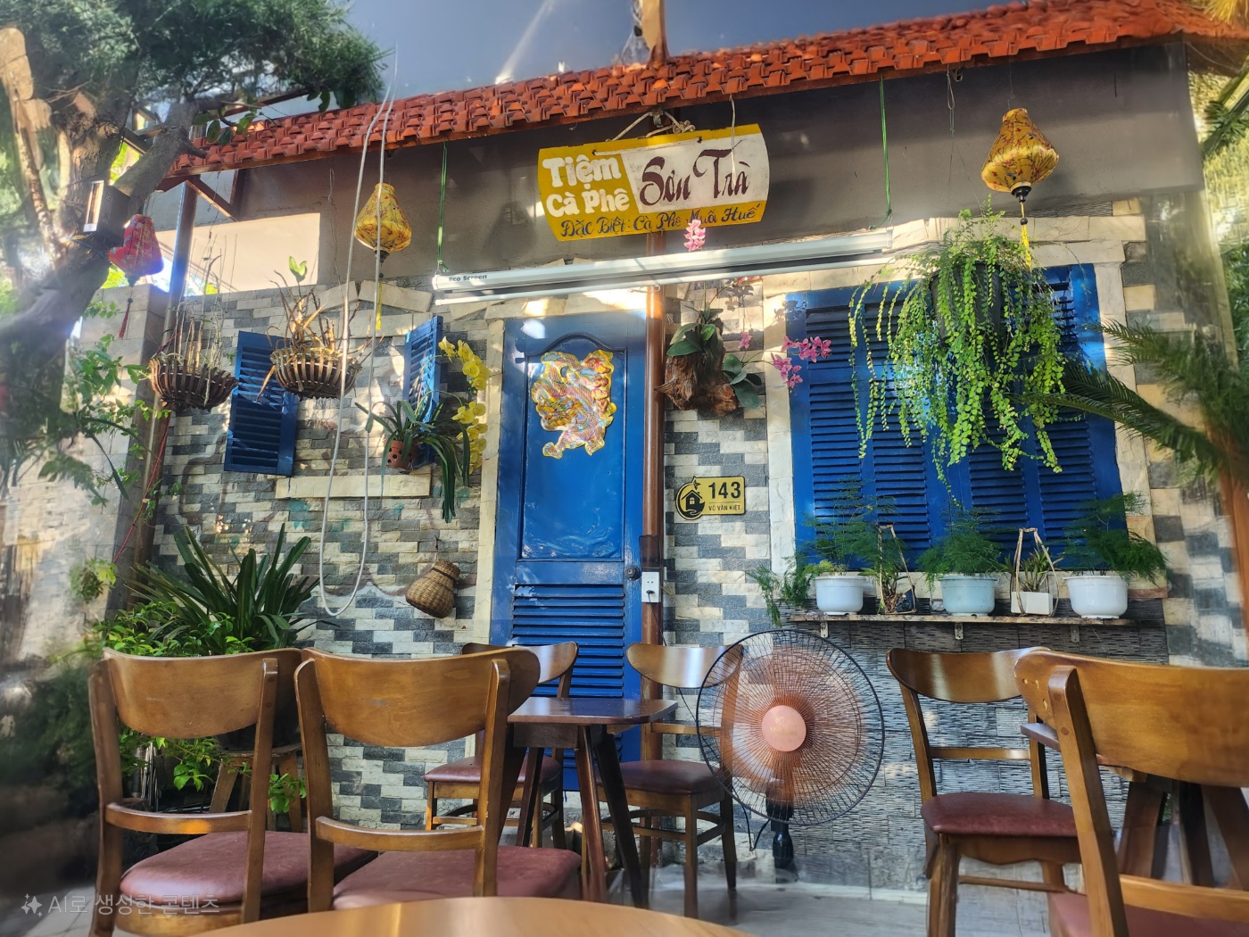 초록 식물과 선명한 파랑문이 멋스럽게 어우러진 다낭 현지 카페 사진