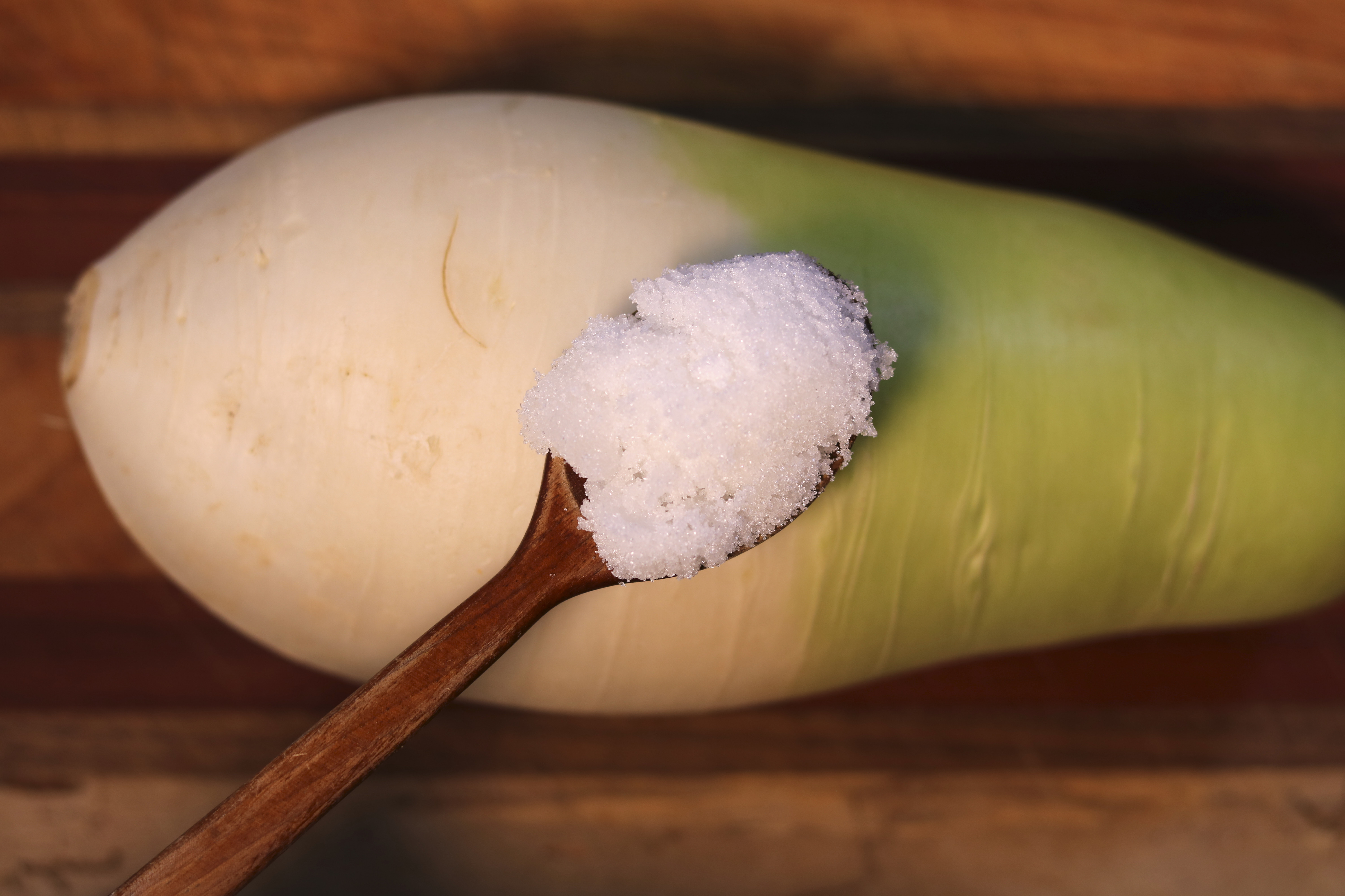 흰색과 초록색이 반반인 무 위에 설탕이 있는 스픈이 있다