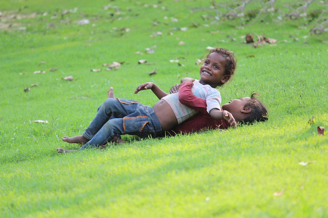 잔디밭에서 딩 구는 행복한 모습의 아이들