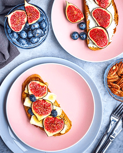 타원형 토스트 위에 치즈가 발라졌고 그 위에 조각난 빨간 무화과들이 있다. 이런 접시가 2개다. 주변엔 블루베리들도 있다.