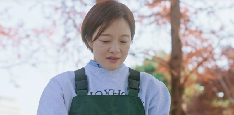 실외에 있는 단풍나무를 배경으로 갈색 숏컷 머리에 작업복을 입고 있는 이 연애는 불가항력의 정민 캐릭터