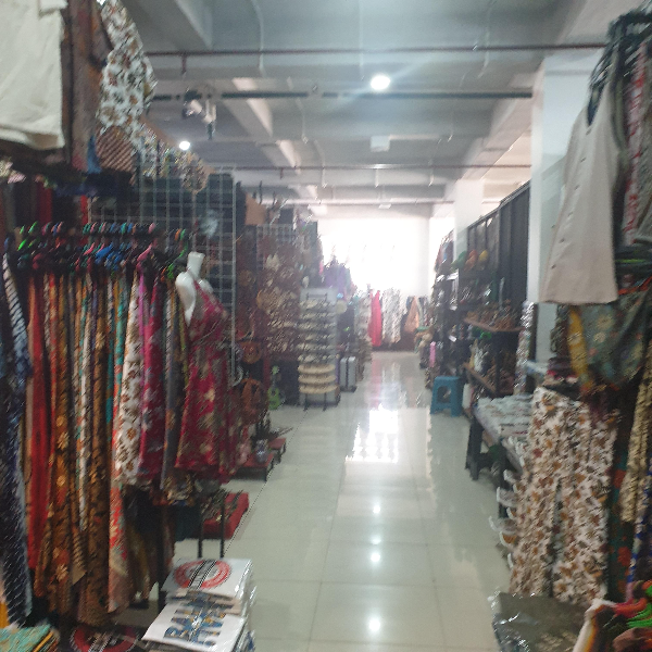 복도를 따라 쭉 어어져 있는 가게들. 가게에는 옷들이 걸려있다.