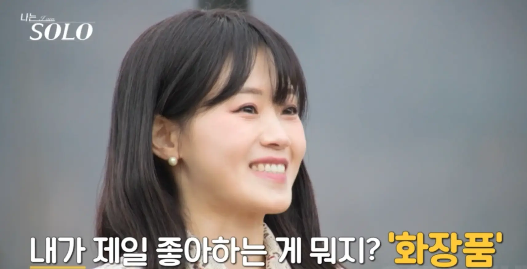 나는 솔로-자연배경 검은리본이 달린 베이지색 원피스 긴웨이브머리를 하고 말하는 현숙의 옆모습 아래 흰글씨 내가 제일 좋아하는 게 뭐지? 화장품