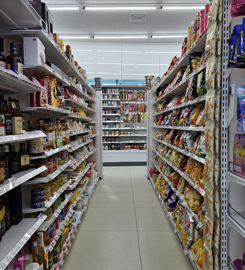 늦은 밤 편의점 간식 매대를 비추는 조명과 진열된 상품들