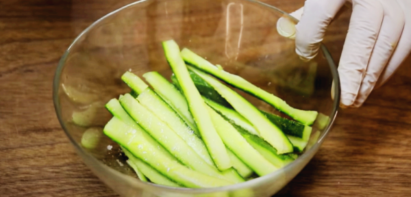 오이를 길게 채 썬 후 설탕, 꽃소금, 식초를 넣어 절이고 있습니다