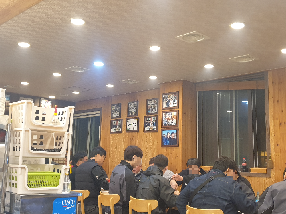 검은 옷을 입은 사람들이 한 곳에 앉아 고기를 먹고 있다.