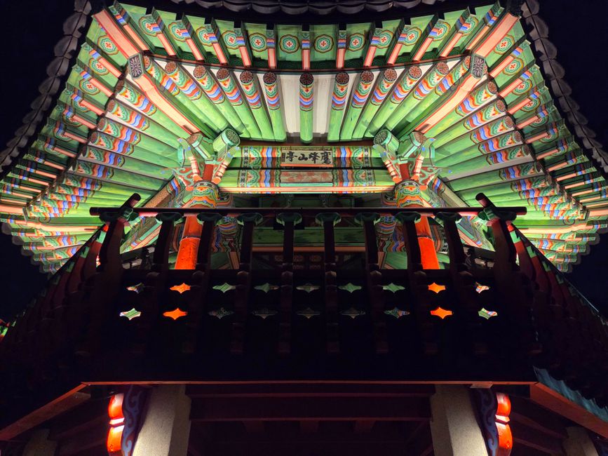 Vividly lit traditional Korean architectural roof at night, showcasing intricate details in Seoul, South Korea.
