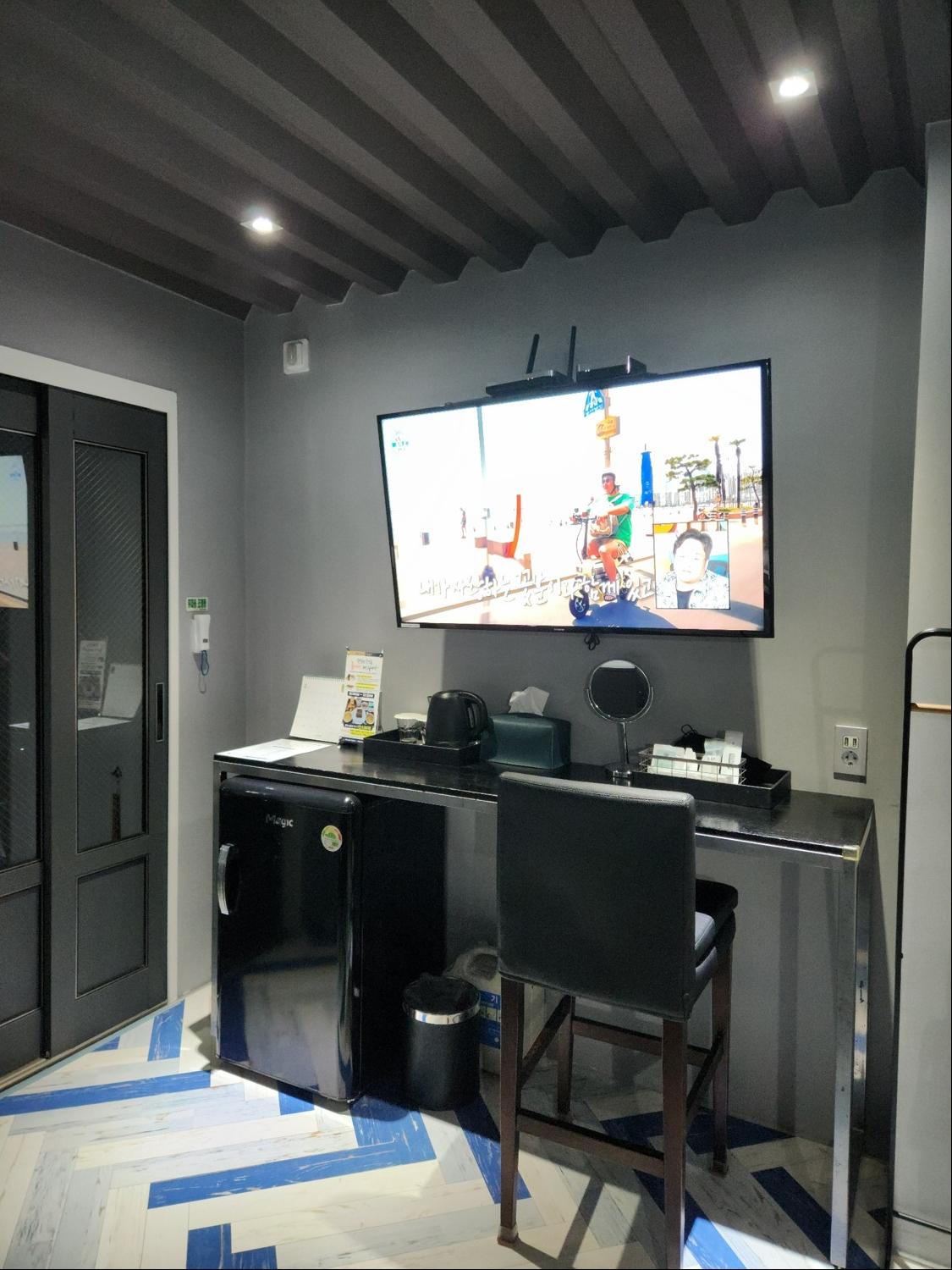 벽걸이 TV&amp;#44; 테이블&amp;#44; 의자가 객실 안에 있다
