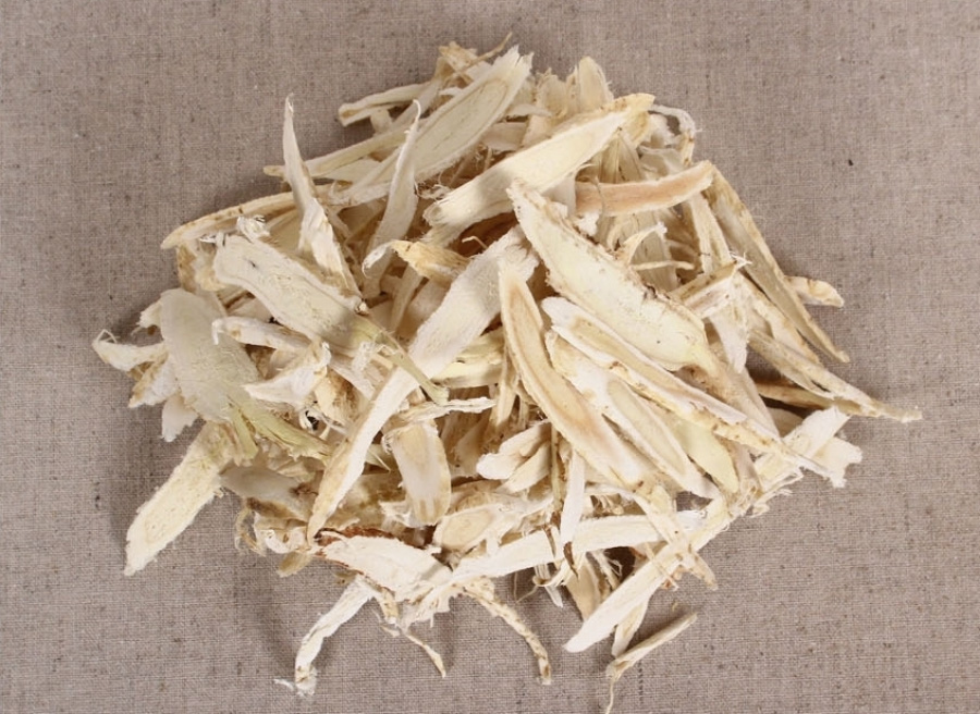 야생에서 채취를 한 황기를 깨끗하게 세척한 후에 편으로 얇게 썰어 놓은 것을 베이지색 바닥 위에 수북하게 놓아두고 찍은 사진