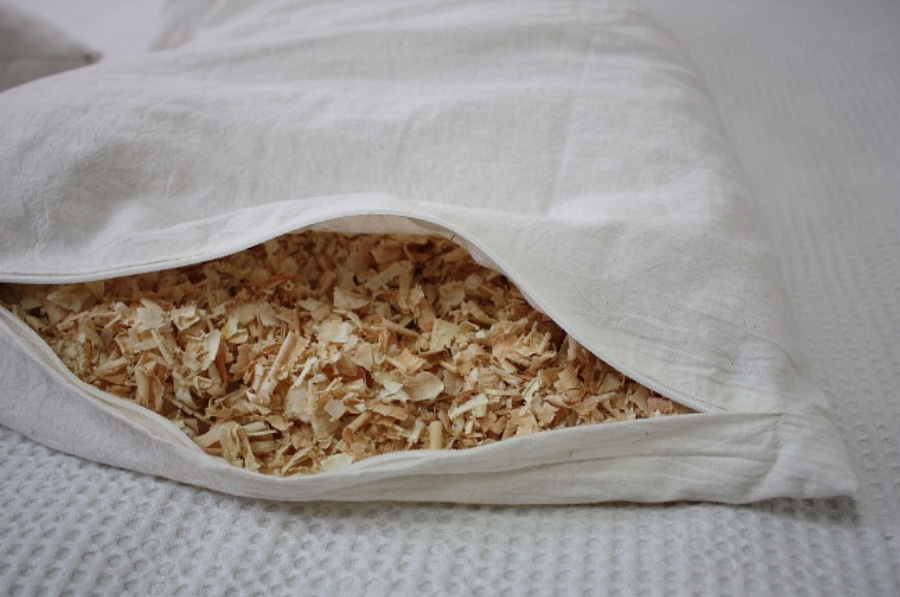 야생에서 채취를 한 편백나무의 대팻밥을 햐얀 베개 속에 가득 넣은 것을 자크를 열어서 속이 보이게 한 상태로 침대 위에 놓고 찍은 사진