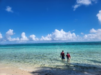 새파란-하늘에-뭉게-구름이-피어있고-바닥까지-훤히-보이는-바다를-여자친구와-함께-들어가는-남자