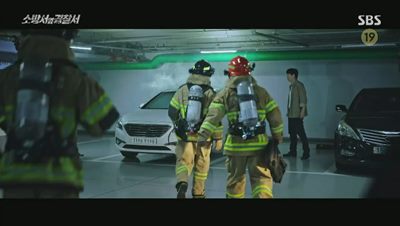 연기로 가득 찬 차에 접근하는 경찰과 소방대원입니다.