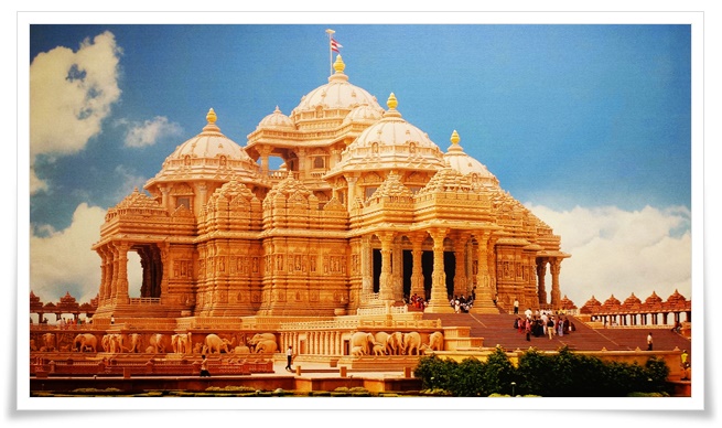 흰 구름이 떠 있는 푸른 하늘과 대비되는 황금빛의 인도 뉴델리 악샤르담 사원의 웅장한 모습. 외관에는 코끼리 조각이 장식되어있다