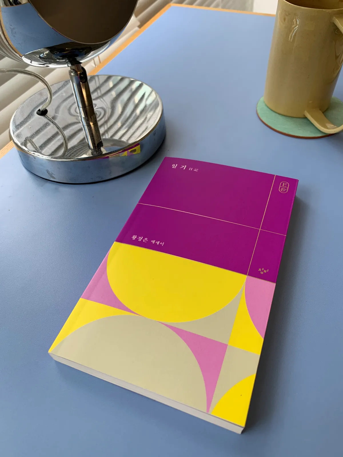 파란색테이블위-보라색책한권과-랩프와-커피컵