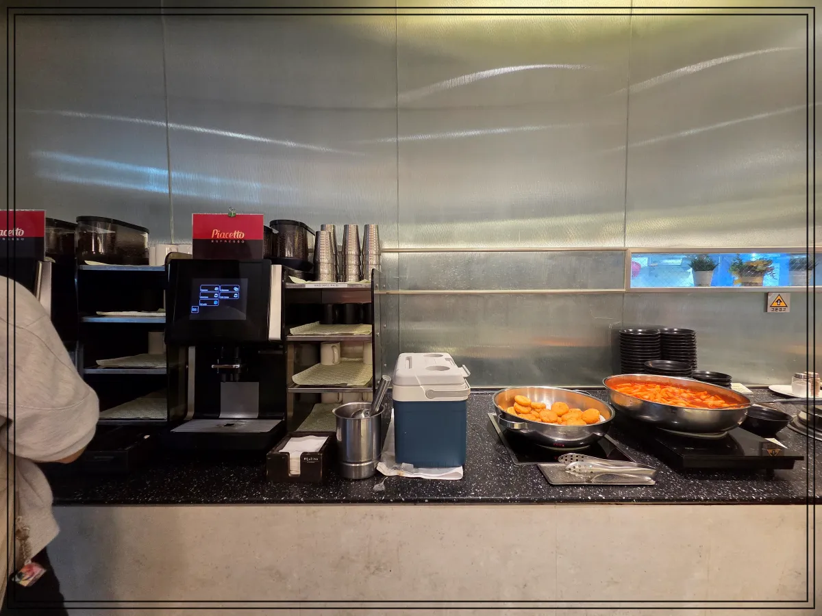 왼쪽에는-피아체토-커피머신과-종이컵-정수기-오른쪽에는-떡볶이와-도넛이-담긴-팬이-배치된-셀프-코너