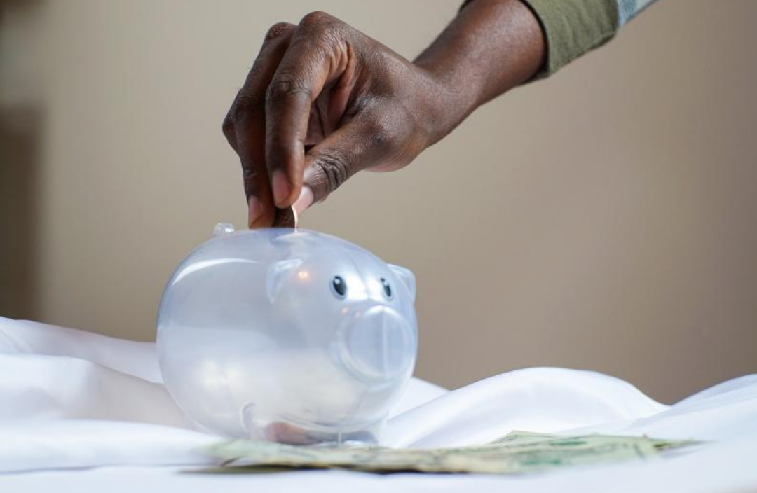 한 남자가 돼지저금통에 동전을 넣고 있다.