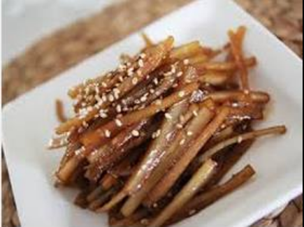 하얀 사각 접시에 담긴 윤기 나는 우엉조림. 간장과 조청으로 졸여진 갈색빛 우엉 위에 볶은 참깨가 뿌려져 있어 고소한 향이 느껴지는 전통 한식 반찬