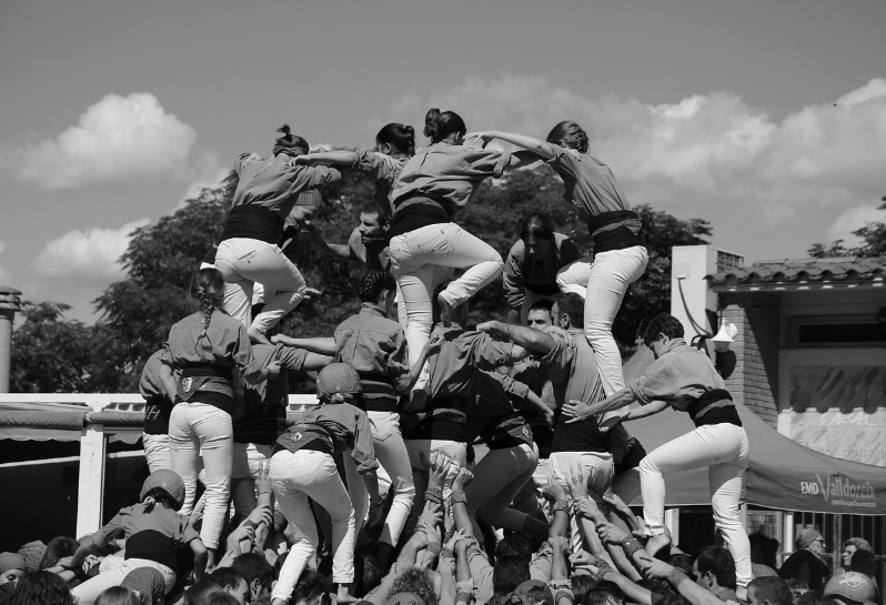 여러 사람이 협력하여 인간 탑을 쌓고 있는 장면, 균형과 협력의 상징적인 흑백 사진