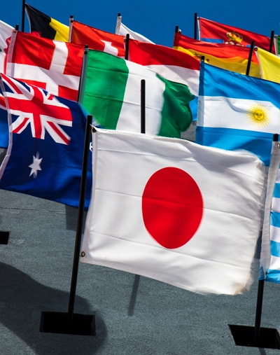 일본 국기 뒤로 다양한 나라들의 국기가 바람에 흔들리고 있는 사진