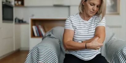 팔꿈치를 부여잡고 있는 여성 사진