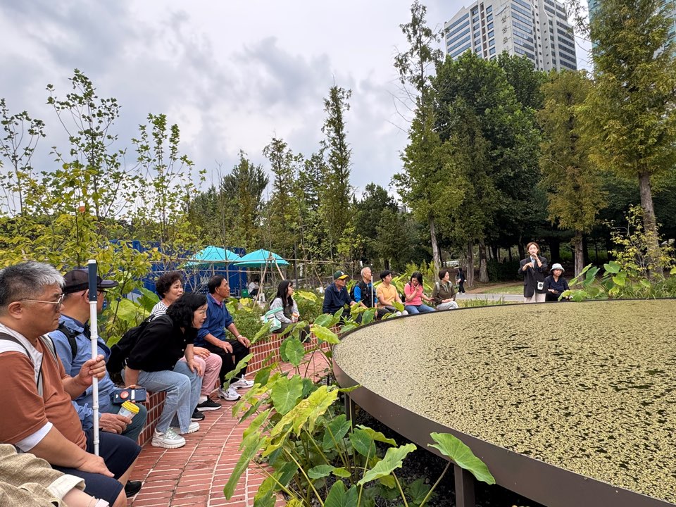 개구리밥이 서식하는 동그란 조형물 앞에 모여서 설명을 듣는 모습