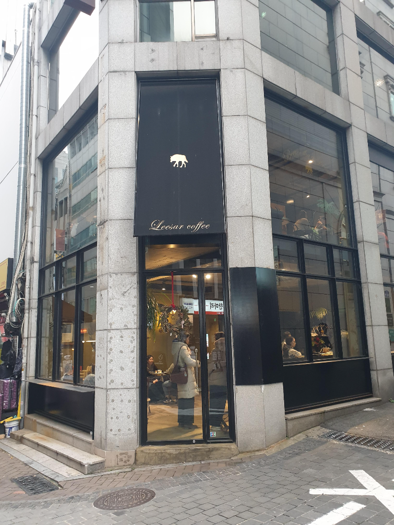 콘크리트와 검은색 프레임과 간판으로 이루어진 카페 외부