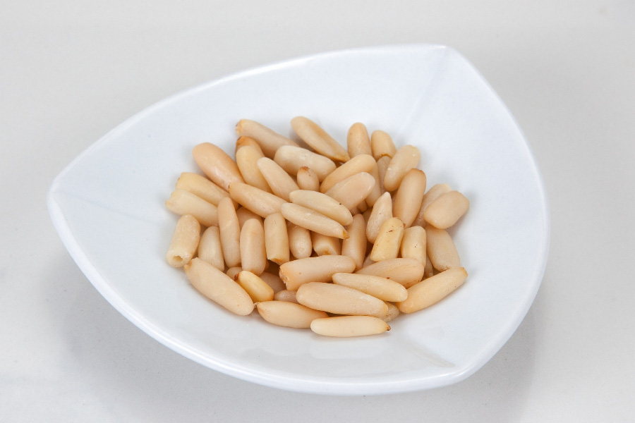 야생에서 채취를 한 해송자, 즉 잣을 껍질을 까서 속 알맹이만 모아서 희고 삼각형 모양의 유리 그릇에 담아두고 찍은 사진
