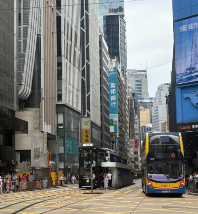 홍콩섬 도심의 모습, 높은 건물들이 줄지어 세워져 있고 2층버스와 트램이 지나다니고 있다.