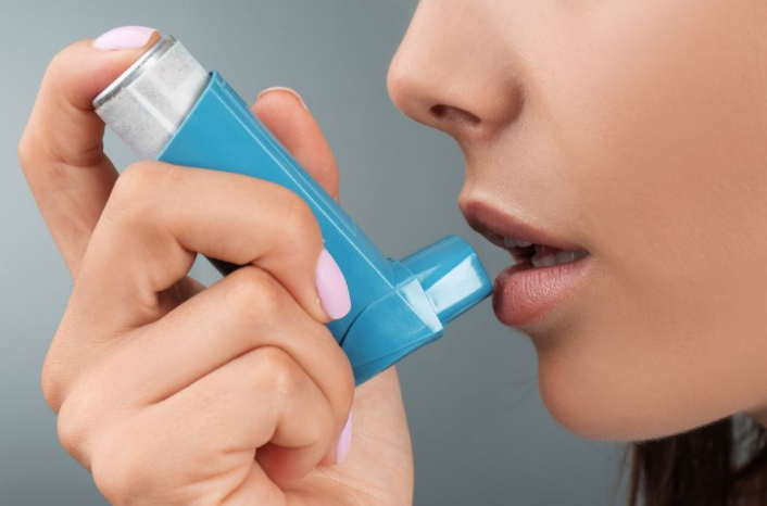 천식으로 천식흡입기를 사용하고는 여자의 모습