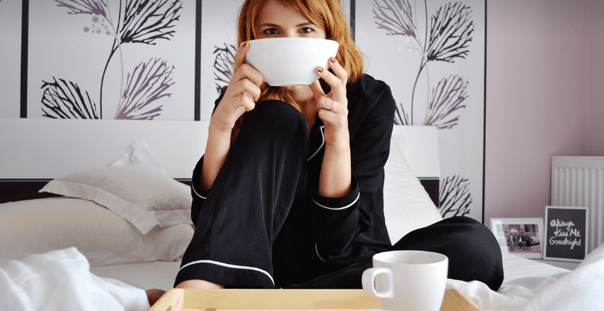 아침에 일어나서 침대에 앉아 아침식사를 하고 있는 여자