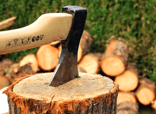 나무 자루와 검정색 날을 가진 도끼가 통나무 그루터기를 찍는 모습이다.
