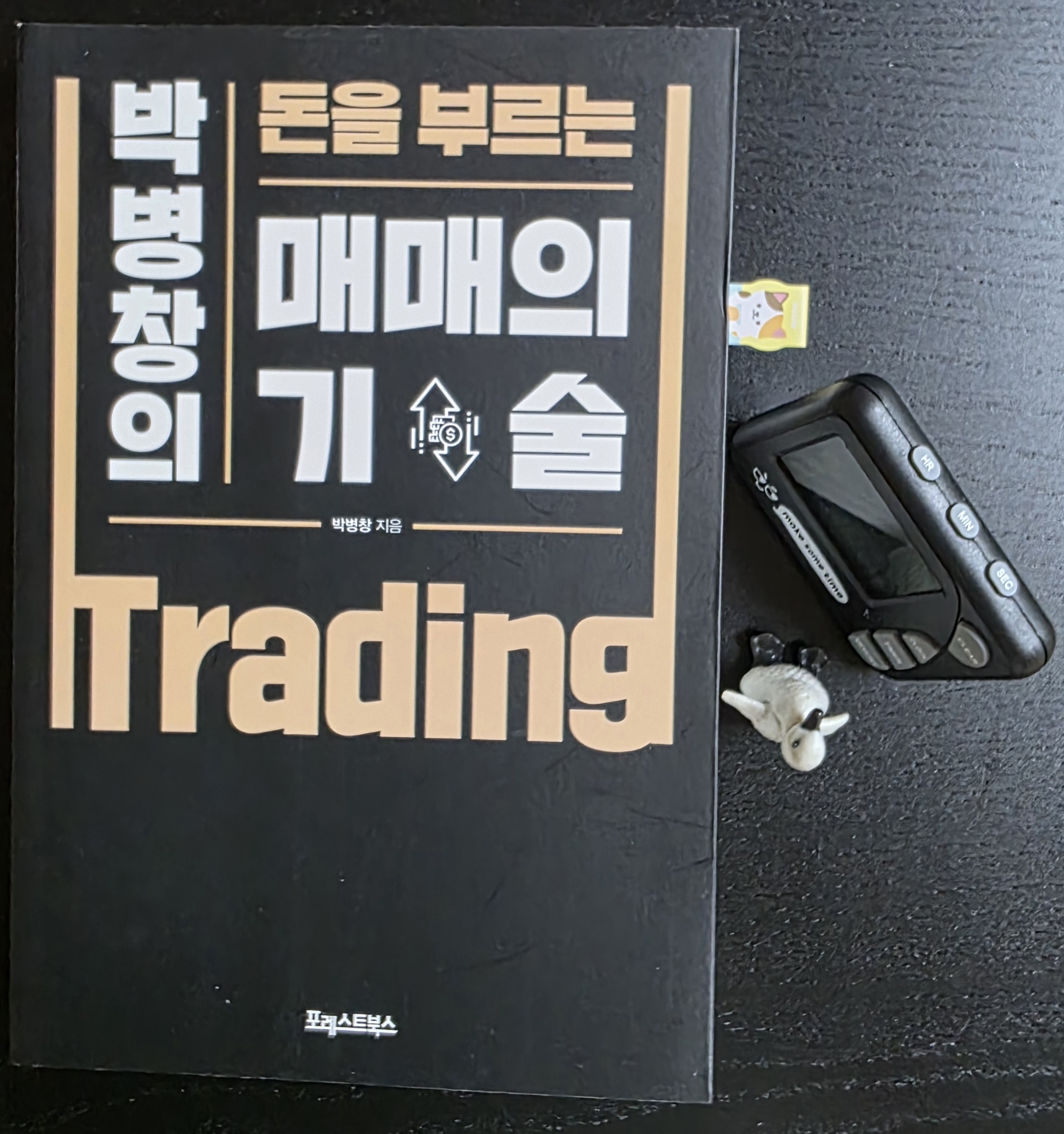 타이머와 펭귄 피규어가 놓인 박병창의 돈을 부르는 매매의 기술 책 표지