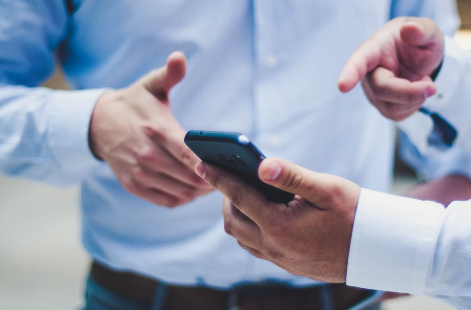 핸드폰을-두고-얘기하는-두-남자의-손