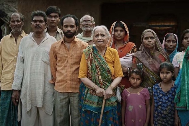 영화 《화이트 타이거》에서 발람의 가족과 마을 사람들이 굳은 표정으로 서 있는 장면. 세습된 가난과 억압, 그리고 그 틀 안에 갇힌 수많은 현실이 화면 가득 담겨 있다.