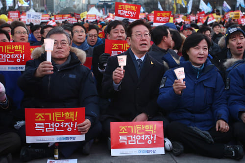 촛불집회에서 문재인과 함께 앉아 쉬위하는 이재명