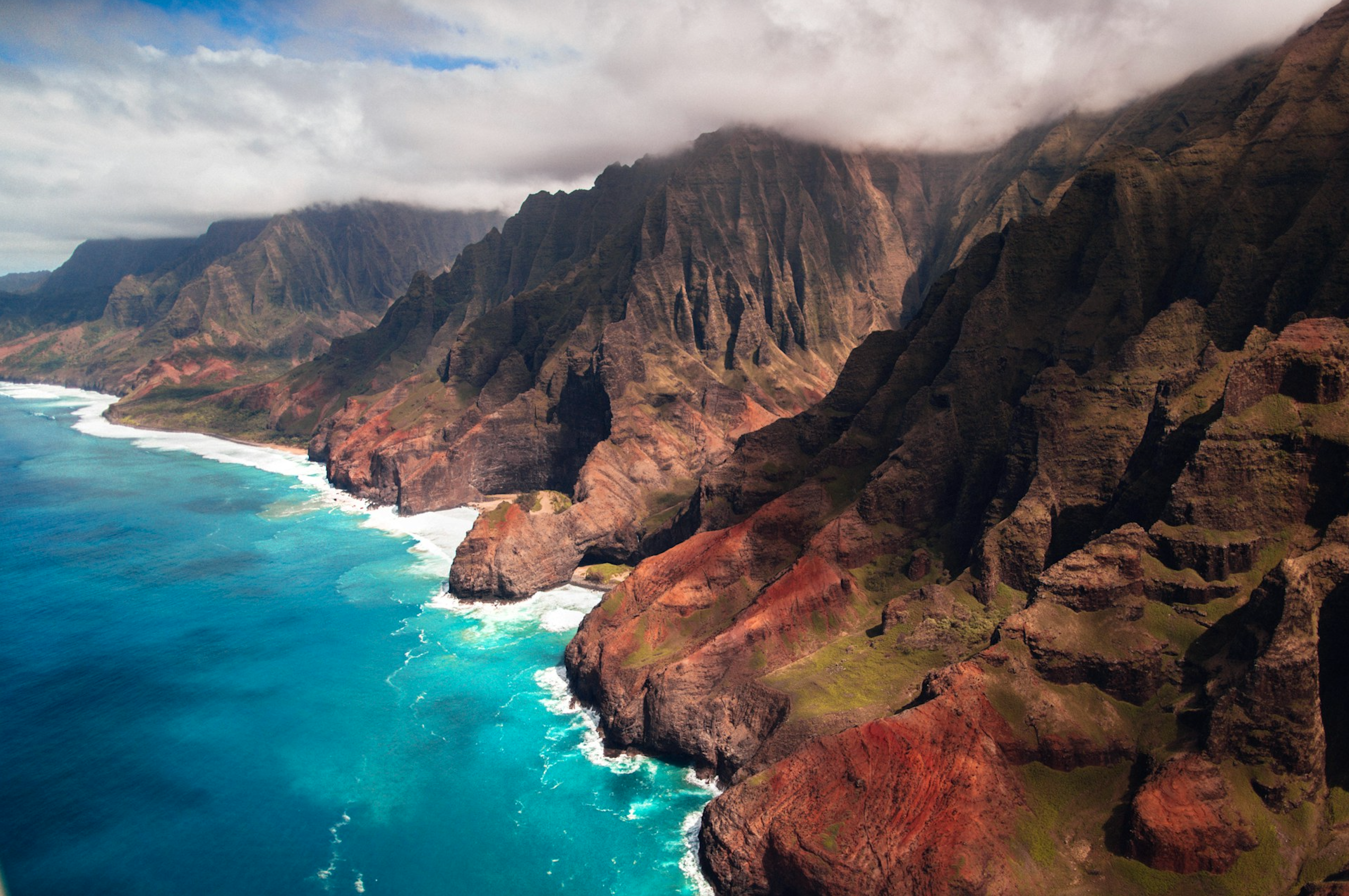 An aerial view of the Na Pali Coast’s rugged green cliffs and blue ocean