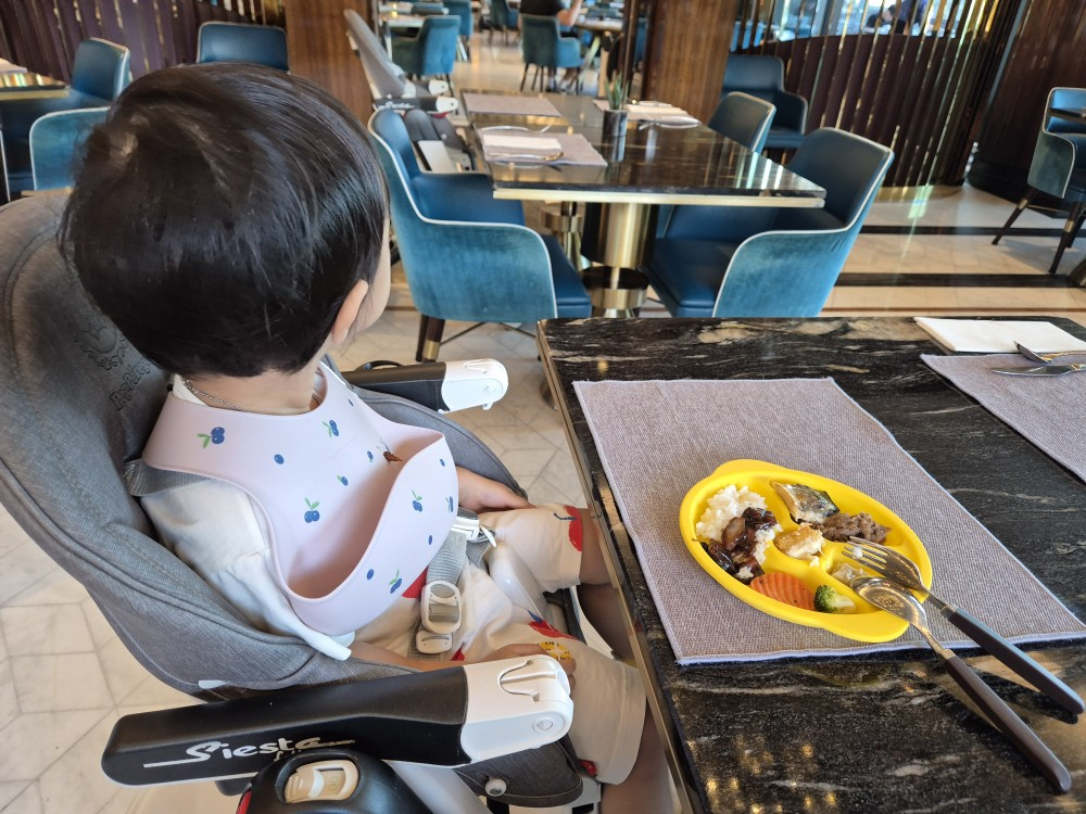 식당 의자에 앉아 고개를 돌린 아기 뒷모습 사진