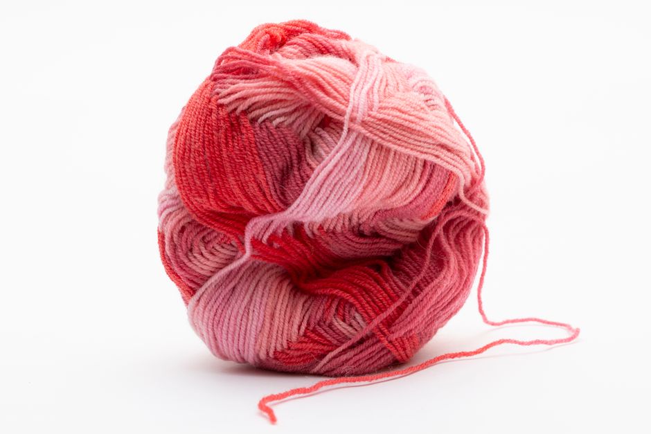 A colorful yarn ball in shades of red and pink isolated on a white background.