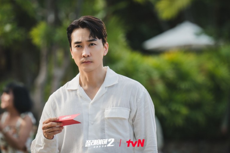 플레이어2 드라마의 한장면. 주인공이 초대장을 받고 내용을 읽어보고 있다.